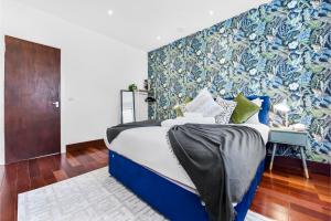 ein Schlafzimmer mit einem blauen Bett mit einer blauen und grünen Wand in der Unterkunft Enchanted Oasis: A Cozy Flat w/ Botanical Charm in Hanwell