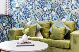 ein Wohnzimmer mit einem grünen Sofa und einem Tisch in der Unterkunft Enchanted Oasis: A Cozy Flat w/ Botanical Charm in Hanwell