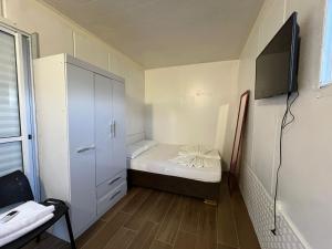 サン・ガブリエウにあるPousada Familiarの小さなベッド1台、テレビが備わる小さな客室です。