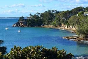 Blick auf einen Strand mit einem Boot im Wasser in der Unterkunft Seabreeze Cottage Bundeena in Bundeena
