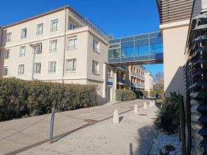 a large white building with a walkway in front of it at GREEN Studio climatisé, vue sur golf proche Montpellier in Montpellier