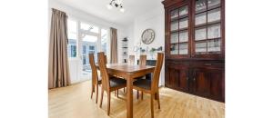 een eetkamer met een houten tafel en stoelen bij City Escape: Sleek and Comfy 3 BR House w/ Garden in Hither Green
