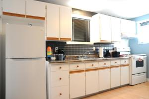 a kitchen with white cabinets and a white refrigerator at Logis des prodiges in Rouyn