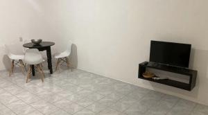 een kamer met een tv en een tafel en stoelen bij Sueño de bugambilia in Oaxaca City