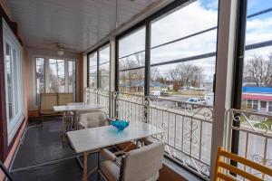 einen Balkon mit Tischen, Stühlen und Fenstern in der Unterkunft 227 Le confort de l'Auberge ! in Trois-Rivières