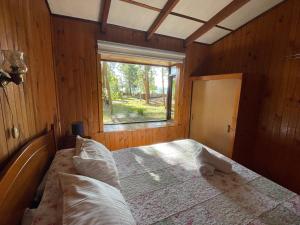 ein Schlafzimmer mit einem Bett in einem Zimmer mit einem Fenster in der Unterkunft Cabañas Vista al Lago in La Ensenada