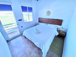 1 dormitorio con cama blanca y ventana grande en oualidia surfhouse, en Oualidia