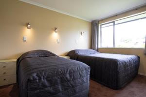 two beds in a room with a window at Annabelle Motel in Hokitika