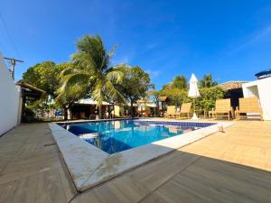 uma piscina com uma palmeira ao lado de um edifício em Chalés Coco Verde - Praia de Itacimirim em Itacimirim