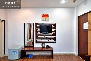 een woonkamer met een tafel en een tv aan de muur bij HANZ Hotel SEN Ben Thanh in Ho Chi Minh-stad