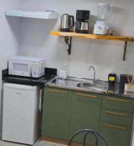uma pequena cozinha com um lavatório e um micro-ondas em Casa Missões Dill Haus 1 em Gramado