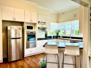 uma cozinha com armários brancos e um frigorífico de aço inoxidável em Four Seasons Home家四季客栈 em Melbourne