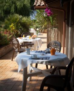 una mesa con mesas blancas y sillas en un patio en Hôtel La Ferme d'En Chon, en Biscarrosse