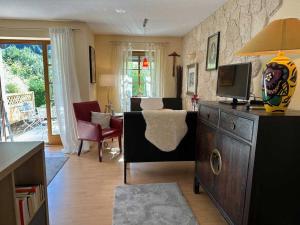 un soggiorno con TV e un soggiorno con divano di Sachrang: Ferien-Wohnung am See mit Bergblick a Sachrang