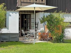 un tavolo e sedie sotto un ombrellone in un cortile di Sachrang: Ferien-Wohnung am See mit Bergblick a Sachrang