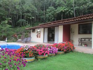 a house with a bunch of flowers next to a pool at Sítio Cachoeirinha in Marechal Floriano