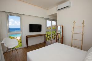 um quarto com uma cama, uma televisão e janelas em Pousada Mar em Mim em Fernando de Noronha