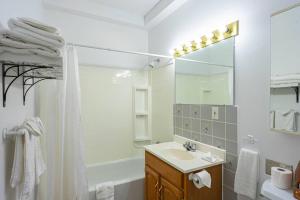 La salle de bains blanche est pourvue d'un lavabo et d'un miroir. dans l'établissement 232 Espace pour l'Aventure familiale, à Trois-Rivières