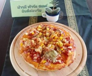 a pizza on a plate on a table at ปารมีฟาร์มสเตย์ in Ban Chao Nam