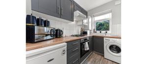 a kitchen with black cabinets and a washer and dryer at Terrific 1 BD Flat in London in London