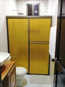 a yellow shower door in a bathroom with a toilet at Baruch Tropical Ranch in Los Santos