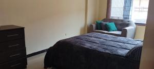 a bedroom with a bed and a dresser and a chair at Departamento Huanchaco in Huanchaco