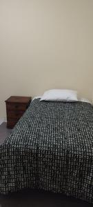 萬查科的住宿－Departamento Huanchaco，一张带黑白棉被的床和一张桌子