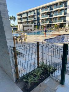 a woman walking by a swimming pool next to a building at Makia114experience in Porto De Galinhas