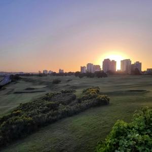 una puesta de sol sobre un campo de golf con una ciudad en el fondo en ALEM en Mar del Plata