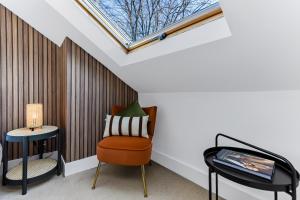 ein Dachfenster in einem Zimmer mit einem Stuhl und einem Tisch in der Unterkunft Tranquil Terra - Cozy and Soothing Vibe in Hanwell