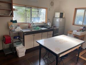 cocina con mesa, fregadero y nevera en Hostel John Mang ゲストハウス ジョン, en Tosa