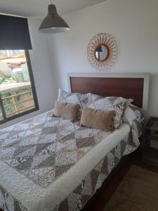 um quarto com uma cama com uma colcha e um espelho em Depto. Playa La Herradura Coquimbo em La Serena