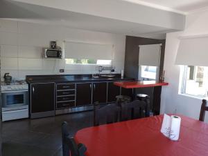 uma cozinha com uma mesa vermelha e uma bancada vermelha em LAS LOMAS em Miramar
