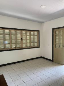 Cette chambre est dotée de murs blancs et de fenêtres à volets en bois. dans l'établissement Paraíso tropical, à Cabo Frio