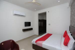 a white bedroom with a bed and a tv at OYO Hotel Vandana in Alwar