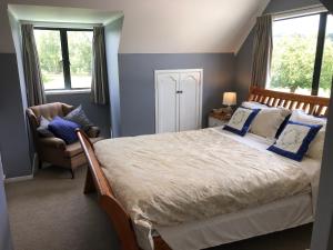 a bedroom with a bed and a chair and windows at Hunua Ranges in Hunua