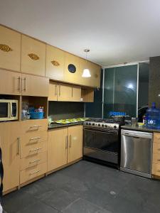 a kitchen with wooden cabinets and stainless steel appliances at El palacio de cristal in Sangolquí