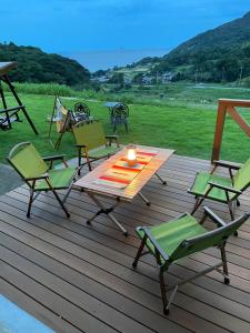 una terraza de madera con sillas y una mesa con una vela en 舞鶴ふるるファームコテージ en Maizuru