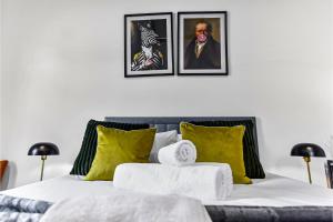 Comfortable 3 Bedroom Apartment in Greater London في Hanwell: غرفة نوم بسرير مع صورتين على الحائط