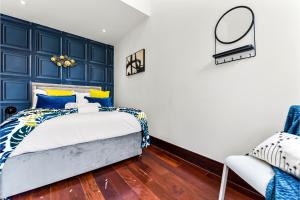 Comfortable 3 Bedroom Apartment in Greater London في Hanwell: غرفة نوم زرقاء وبيضاء مع سرير وكرسي