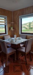 d'une salle à manger avec une table, des chaises et une fenêtre. dans l'établissement cabaña los teros, à Coyhaique