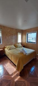 a large bed in a bedroom with wooden walls at cabaña los teros in Coihaique