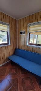 a blue couch in a room with two windows at cabaña los teros in Coihaique