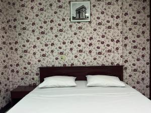 uma cama com duas almofadas num quarto com papel de parede floral em Woodlands Inn em Bangkok