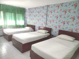 Duas camas num quarto com papel de parede floral em Woodlands Inn em Bangkok
