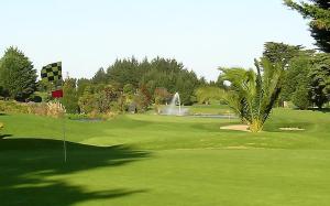 a green golf course with a fountain in the background at Clarks Beach Getaway in Clarks Beach
