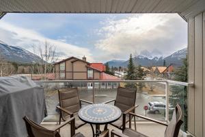 a balcony with a table and chairs and a view of mountains at Parkland301 Sunlit 2,000 ft² Penthouse with Mtn View in Canmore