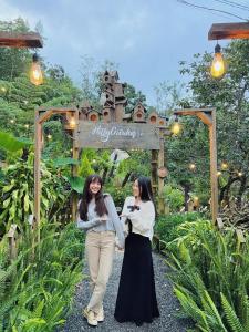 deux femmes qui marchent sur un chemin dans un jardin dans l'établissement Kim Đồng homestay, à Buôn Enao