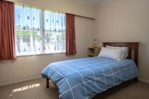 a bedroom with a blue bed and two windows at Glenview home in Hamilton