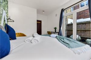- une chambre avec un lit blanc et des serviettes dans l'établissement Lovely 2-bedroom rental unit in Greater London, à Hanwell